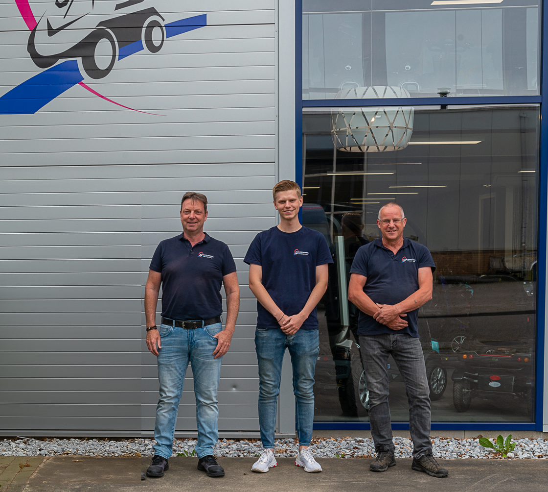 Een foto met de drie personeelsleden van Scootmobiel Friesland. Ze staan voor de showroom